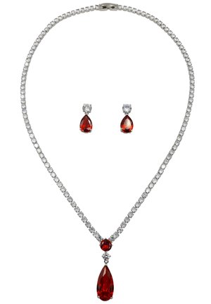 Collana di gemme rosse con catena in argento, caratterizzata da un pendente a goccia e orecchini abbinati decorati con piccole pietre trasparenti.