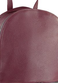 Bordeaux leren rugzak met een gestructureerd oppervlak, ronde bovenkant en zilveren ritsdetails. Inclusief verstelbare schouderbanden voor gemakkelijk dragen.