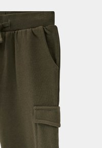 Pantalons de survêtement vert olive en mélange de coton doux, dotés d'une taille côtelée, d'une poche latérale et d'un ourlet élastiqué, conçus pour le confort et l'utilité.
