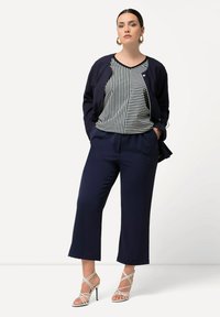 Námořnické zkrácené kalhoty spárované s proužkovaným černobílým topem a odpovídajícím námořnickým sakem. Doplněné o sandály na vysokém podpatku se řemínky.