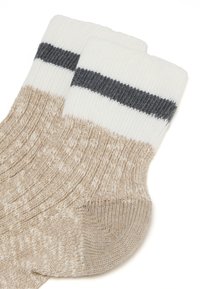Calze in maglia beige con una trama a costine, con strisce bianche e grigie scure nella parte superiore. Punta arrotondata con un tallone leggermente più chiaro.