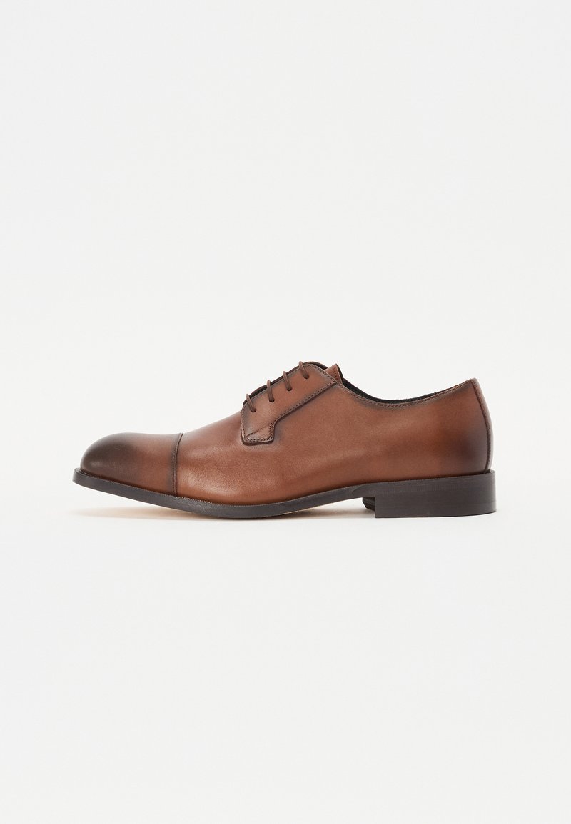 Scarpa da uomo in pelle marrone con punta rotonda, quattro occhielli per i lacci e una finitura liscia. Presenta un tacco leggero e una punta a contrasto.
