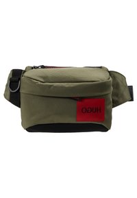 Saszetka na biodro z oliwkowozielonego materiału, z czarnym suwakiem, regulowanym paskiem i czerwoną naszywką z odwróconym czarnym napisem "HUGO".