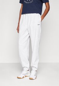 Lichtgrijze joggingbroek van katoen, met een taps toelopende pasvorm en elastische boorden. Gecombineerd met een navy cropped T-shirt en witte sneakers.