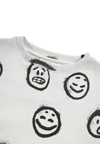 Grå sweatshirt med rund halsringning, prydd med olika svarta leende ansikten på framsidan. Slät textur med ribbade manschetter och krage.