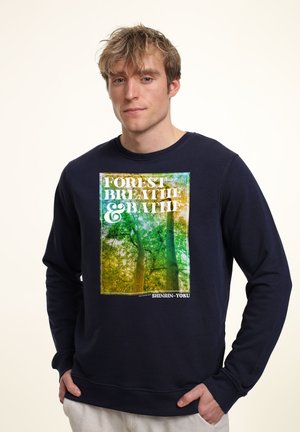 Felpa blu navy con una grafica colorata di alberi e la scritta "FOREST BREATHE & BATH". Materiale misto cotone con polsini a coste.