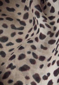 Beige stof med et leopardprintmønster, der har pletter i mørkebrun og sort. Teksturen ser blød og vævet ud.