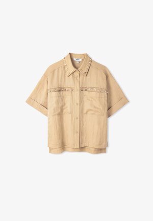 Camisa beige de manga corta, con un cuello puntiagudo y tachuelas decorativas en el cuello y los bolsillos del pecho. Tejido texturizado.