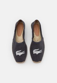 Espadrilles en toile marine avec semelles en jute tissé. Présentent un logo crocodile blanc brodé sur le dessus. Semelle intérieure en cuir lisse.