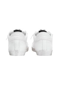 Un paio di sneakers bianche viste dal retro, con toppe sul tallone testurizzate e suole leggermente usurate, su uno sfondo bianco.