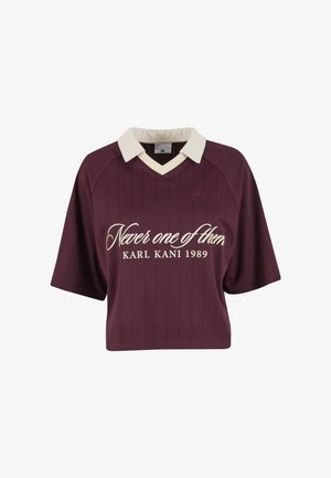 Burgundia lühikeste varrukatega polo särk kreemja kraega, millel on vertikaalne triibumuster ja trükitud tekst "Never one of them KARL KANI 1989."