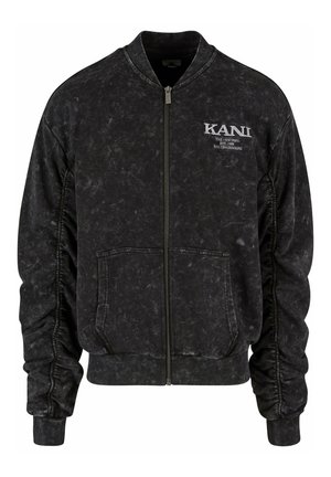 Chaqueta bomber de mezclilla negra con cremallera frontal, puños acanalados y un logotipo en relieve en el pecho. Cuenta con bolsillos laterales y una tela texturizada.