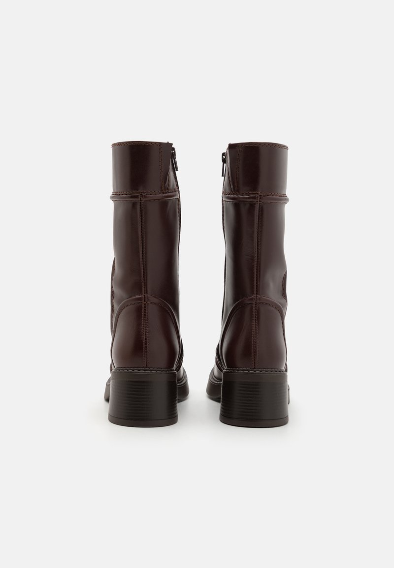 Brune læder ankelstøvler med en glat overflade, rektangulær hæl og lynlås på siden. Har syninger langs sømmene.