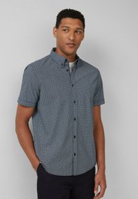 Korte mouwen overhemd in marineblauw met een geometrisch patroon. Voorzien van een kraag, voorknoopsluiting en een ruime pasvorm. Soepele stoftextuur.