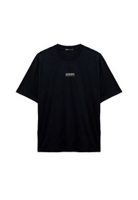 Camiseta negra de manga corta con un pequeño logo rectangular blanco y texto centrado en el pecho.