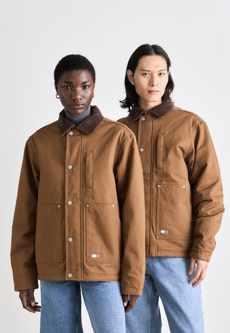 Brune bomuldsjakker med kordfløjlskraver, to forlommer og trykknaplukninger. Casual pasform, båret over lyse turtlenecks og blå jeans.