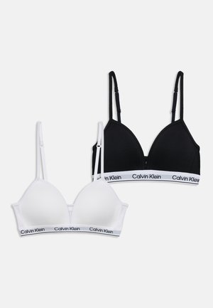 Deux bralettes Calvin Klein, une blanche et une noire, avec des bretelles réglables et des bandes élastiques à logo en bas.