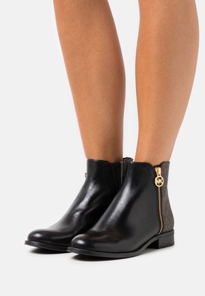 Mustat nahkaiset nilkkurit, joissa on sivuvetoketju kultaisilla koristeilla ja kuvioitu ruskea paneeli. Sileä pinta, pyöreä kärki, matala korko.