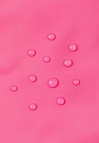 Tessuto rosa caldo con gocce rosa lucide di varie dimensioni sparse sulla superficie, creando un effetto visivo testurizzato.