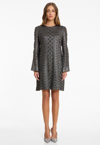 Kurzes, knielanges Kleid in metallischem Schwarz mit geometrischen Mustern und offenem Schulterdesign. Glatte Textur mit subtilen Schimmereffekten.