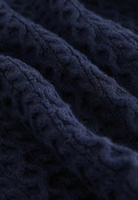 Marineblåt strikket stof med et struktureret kabelmønster, der har en blød, fuzzy overflade og bløde bølger, ideelt til tøj eller hjemme tekstiler.