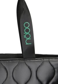 Svart quiltad handväska med en texturerad yta, en övre kant med en slät finish och en grön tryckt logotyp på ett svart band.