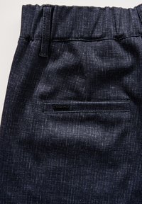 Mörkblå byxor i texturerad tyg med elastisk midja och en bakficka med en svart etikett.