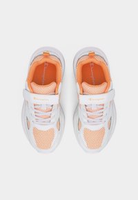 Baskets pour enfants en maille blanche et orange avec sangles velcro et lacets, vues de dessus sur un fond uni.