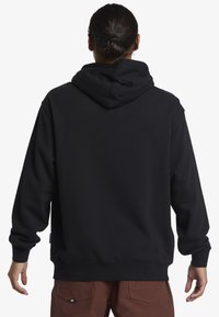 Sudadera negra con capucha y corte relajado, que cuenta con un bolsillo canguro y puños de canalé. Textura suave y diseño sencillo.
