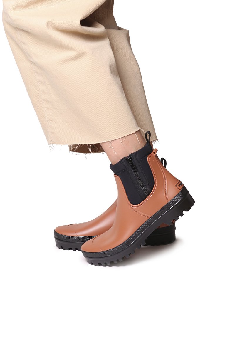 Bruna gummistövlar med svarta elastiska sidor, en strukturerad svart sula och en bakre dragflik; slät yta med kontrasterande accenter.