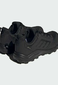 Zapatillas deportivas negras con parte superior sintética texturizada, paneles de malla y suela de goma resistente. Presentan un logo y detalle impermeable de Gore-Tex.