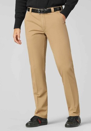 Beige Chinos aus Baumwollmischung mit geradem Bein, Fronttaschen und einem schwarzen Leder-Gürtel. Kombiniert mit schwarzen Sneakers.