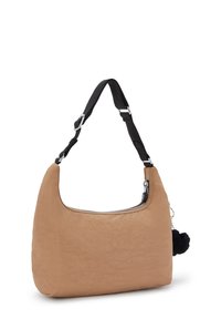 Vaaleanruskea kangasgalleria, jossa on kaareva muoto, musta säädettävä olkahihna, vetoketjukiinnitys ja musta pompomi-yksityiskohta sivulla.