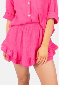 Ensemble en coton texturé rose comprenant une chemise ample avec des boutons et une jupe à ourlet froncé élastiqué.
