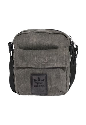 Szara torba na ramię Adidas z przednią kieszenią z patką i czarnym regulowanym paskiem, z naszywką z logo Adidas na przedniej kieszeni.
