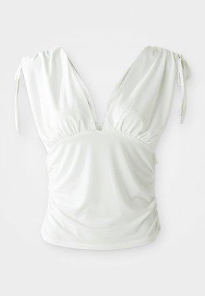 Top blanc sans manches avec un décolleté en V profond et des côtés froncés, comportant des bretelles à nouer ajustables pour un ajustement personnalisé. Tissu lisse et extensible.