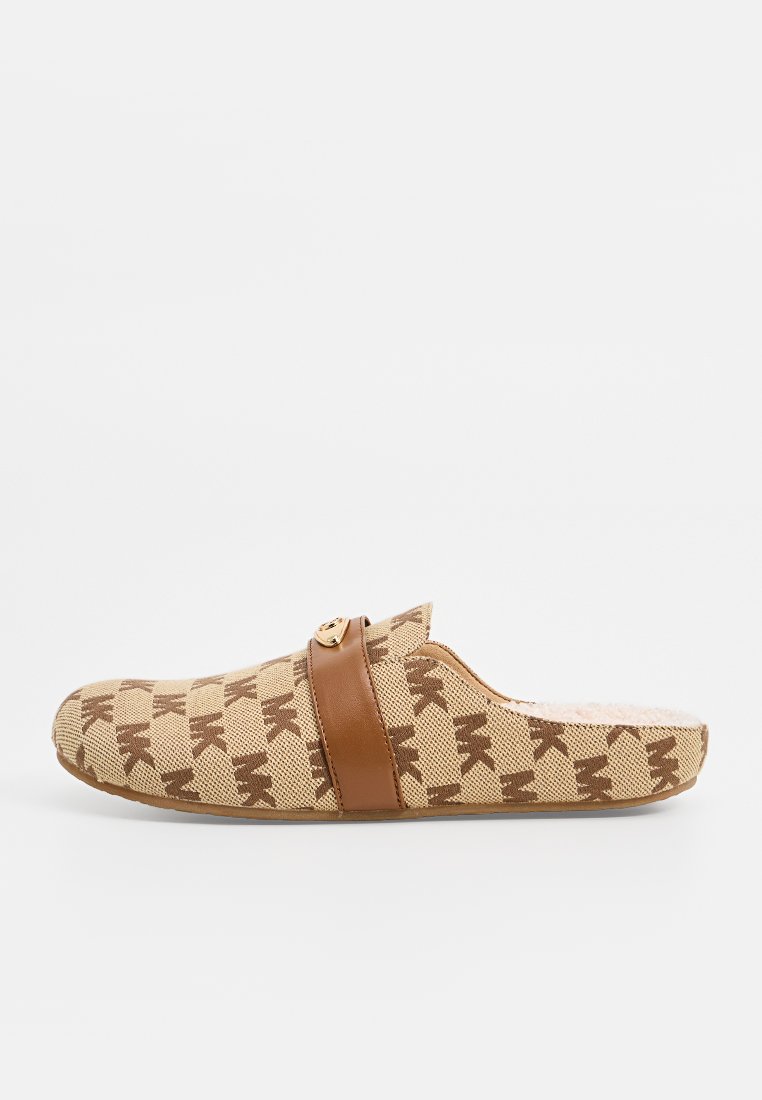 Beige slip-on klogs med ett brunt logomönster, läderrem över toppen och en plyschinredning för komfort. Platt sula.