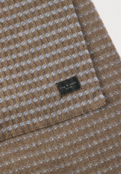 Couverture en tissu marron avec un motif texturé de petits points bleu clair et une étiquette noire portant l'inscription "rag & bone New York". Le bord est fini par une couture.