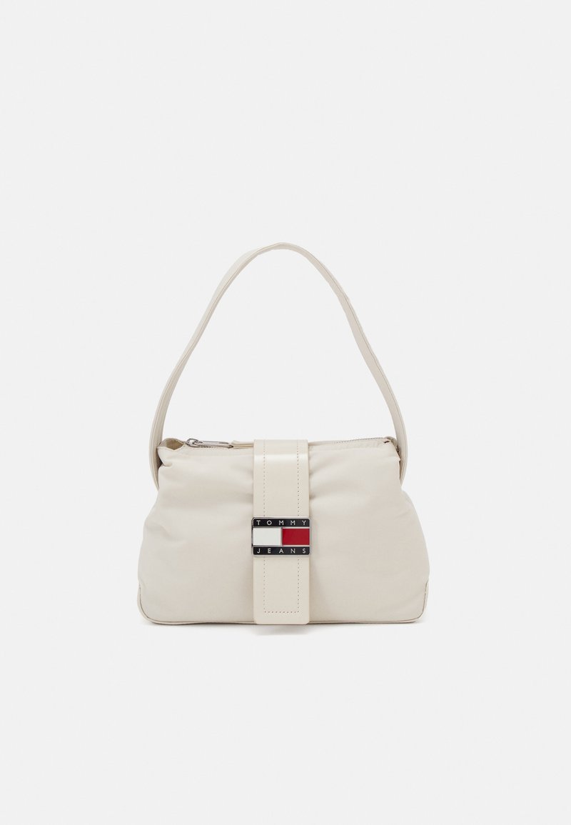 Beige nylon håndveske med en buet fasong, et håndtak på toppen og en kontrasterende rektangulær stropp med en logo i rød, hvit og blå.