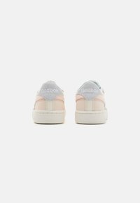 Reebok tenisky s pastelovo ružovým a svetlo šedým zvrškom, mäkkým koženým materiálom, textúrovanou gumovou podrážkou a logom na päte.