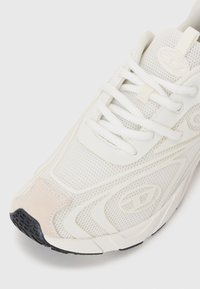 White mesh sneaker with a smooth design, featuring tonal laces, a suede toe cap, rubber sole, and subtle branding on the side.