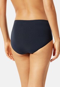 Sous-vêtements taille haute en navire fabriqués dans un tissu doux, présentant un design lisse et sans couture, avec une délicate couture le long de la taille.