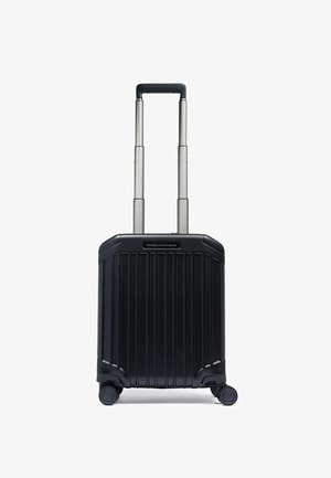 Schwarzer Hartschalen-Koffer mit vertikalen Rillen, ausziehbarem Griff und vier Rollen. Verfügt über eine glatte Oberfläche und ein minimalistisches Design.