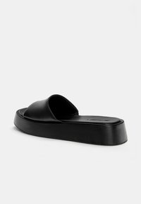 Black slide sandal featuring a wide, rounded strap and a thick platform sole. Smooth texture with minimal detailing.