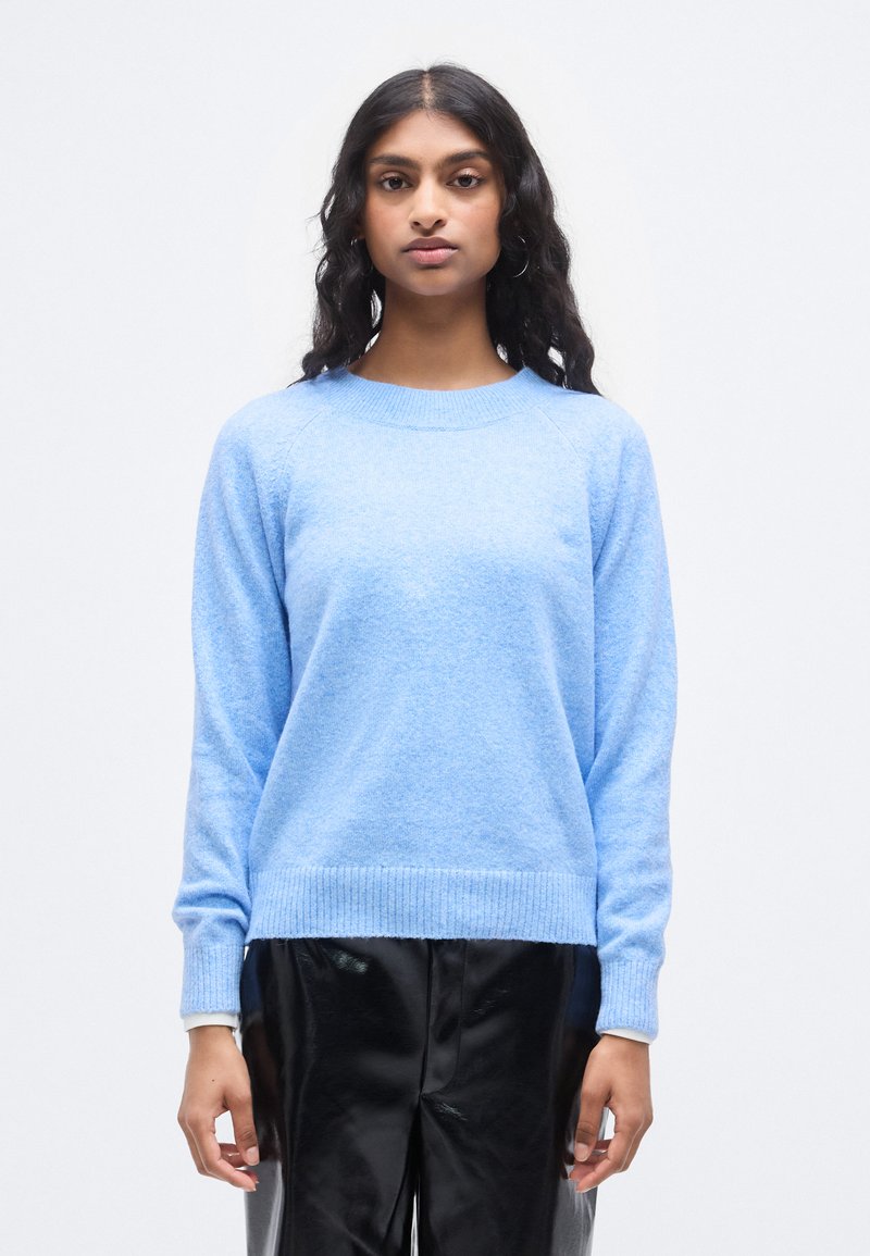 Ανοιχτό μπλε πουλόβερ από μαλακό, υφασμάτινο ύφασμα με υφή. Διαθέτει στρογγυλή λαιμόκοψη, ριμπ μανσέτες και τελείωμα, συνδυασμένο με λαμπερό μαύρο παντελόνι από ψεύτικο δέρμα.