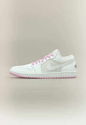 Biały niski sneaker z różowymi sznurowadłami i różowymi akcentami na podeszwie, z perforowaną boczną częścią i logo Nike swoosh.
