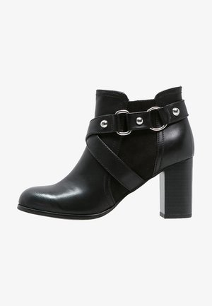 Bottines en cuir noir avec une finition lisse, dotées d'une large sangle croisillon et de quincaillerie argentée, reposant sur un épais talon.