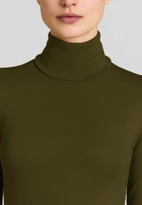 Maglione a collo alto verde oliva con un design aderente e texture liscia. Il collo è alto e privo di cuciture.