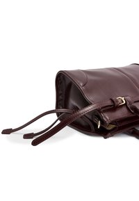 Bordeauxfarbene Lederhandtasche mit glatter Textur, quadratischer Form, Oberseite mit Zugkordelverschluss und Akzenten in goldfarbener Hardware.