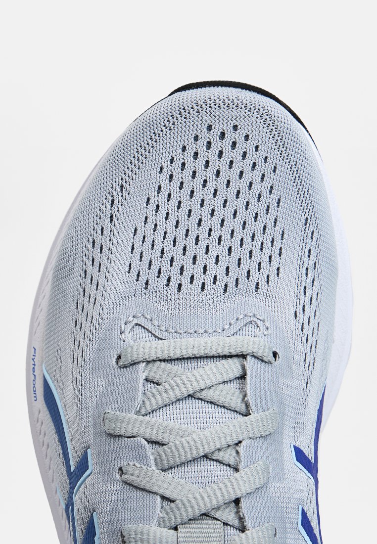Hellgraue Sportschuhe mit einem atmungsaktiven Mesh-Obermaterial, blauen Akzenten und flachen Schnürsenkeln. Verfügt über ein perforiertes Design zur Belüftung.